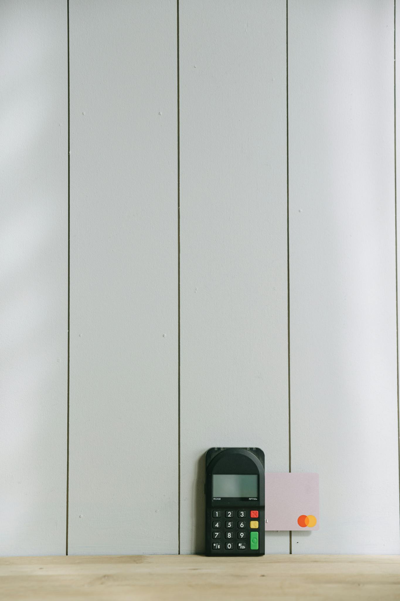 A sleek payment terminal with buttons against a white wooden background, ideal for finance concept.
